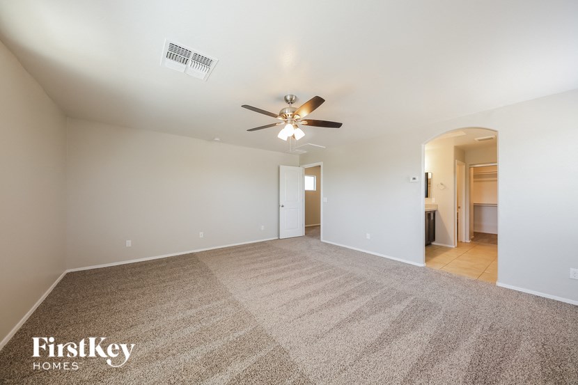 a spacious living room with carpet and a ceiling fan