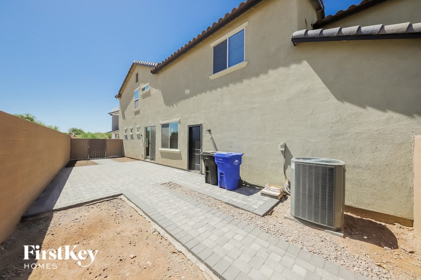 a side view of a house with a driveway and trash cans