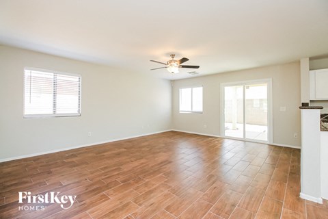 A spacious room with wooden flooring and a ceiling fan.
