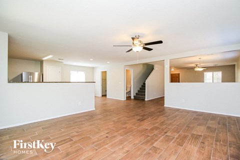 A spacious room with wooden flooring and a ceiling fan.