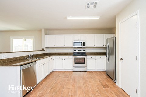 A kitchen with white cabinets and a refrigerator.