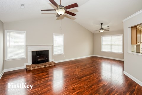 A spacious room with a fireplace and wood flooring.