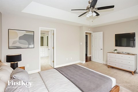 A bedroom with a bed, dresser, and ceiling fan.