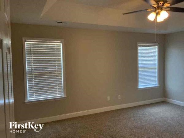a living room with a ceiling fan and two windows