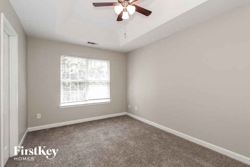 an empty room with a ceiling fan and a window