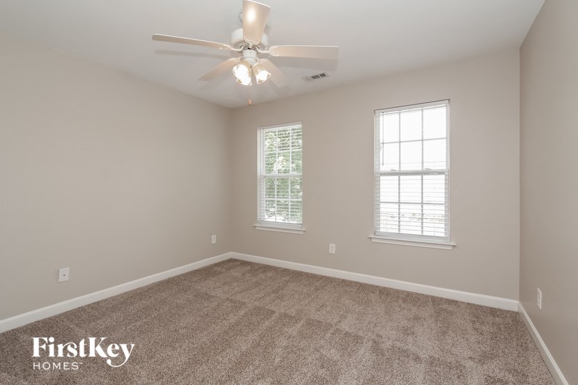 the bedroom with carpet and ceiling fan and two windows