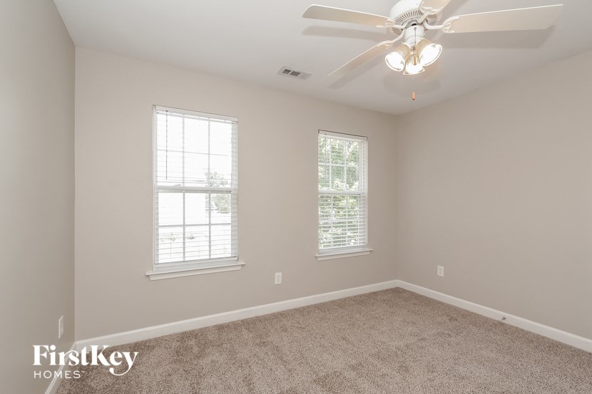 a bedroom with a ceiling fan and two windows