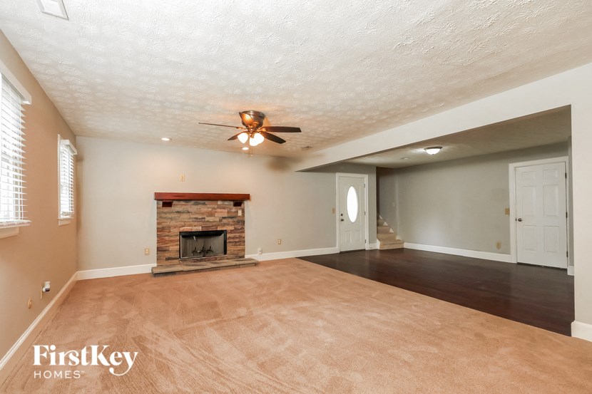 an empty living room with a fireplace and a ceiling fan
