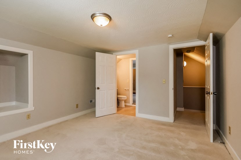 an empty living room with a toilet and a door to a bathroom