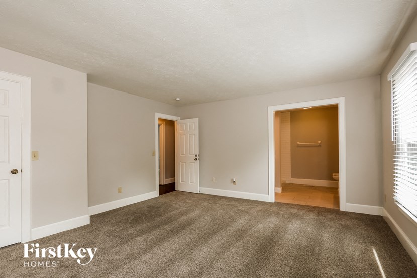 an empty living room with a door to a hallway and a window