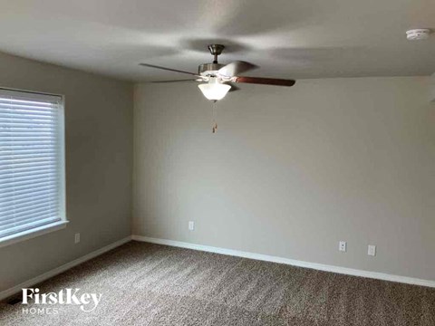 an empty bedroom with a ceiling fan and a window