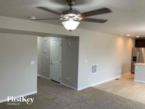 an empty living room with a ceiling fan and a door