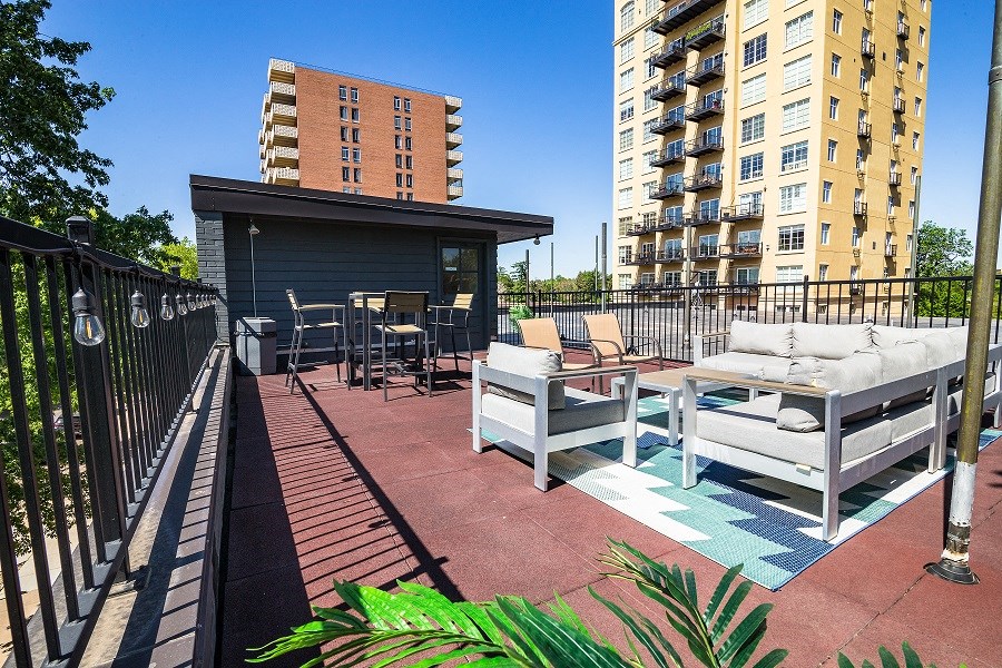 a rooftop patio with furniture and a building in the background