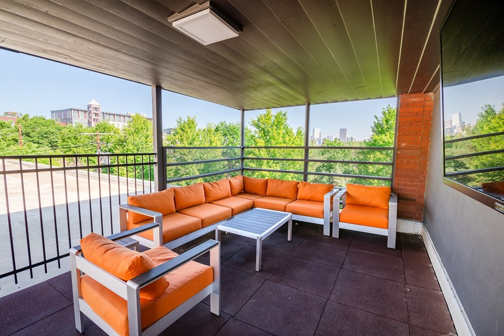 a patio with orange couches and a table on a balcony
