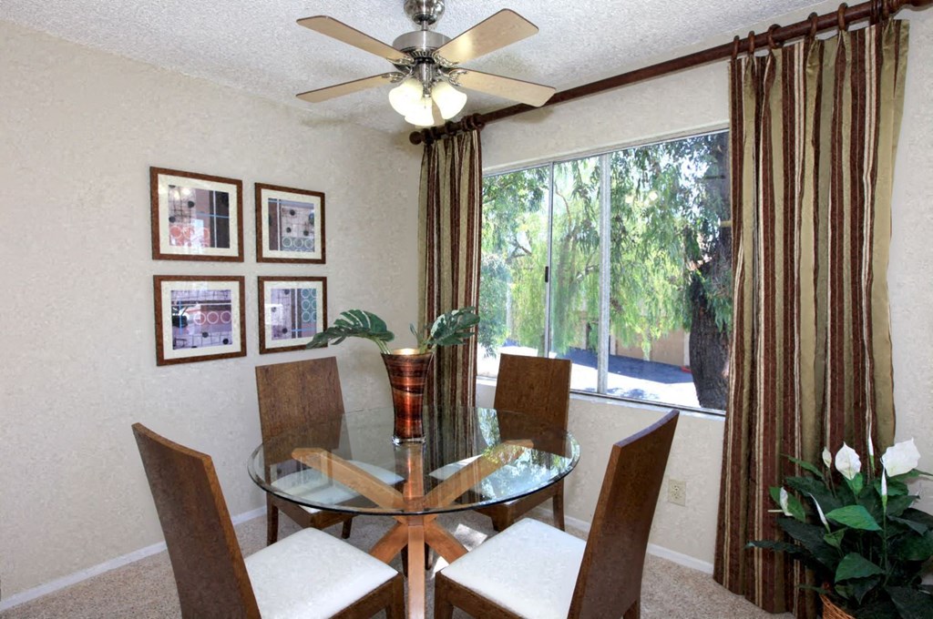 a dining room with a glass table and chairs and a ceiling fan