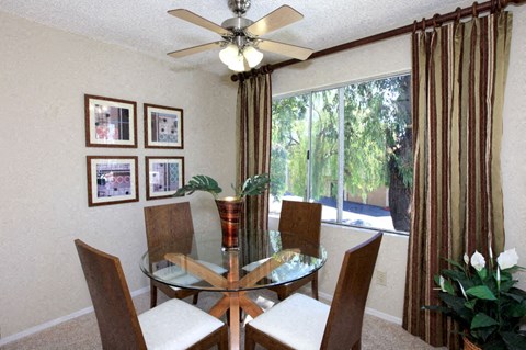 a dining room with a glass table and chairs and a ceiling fan