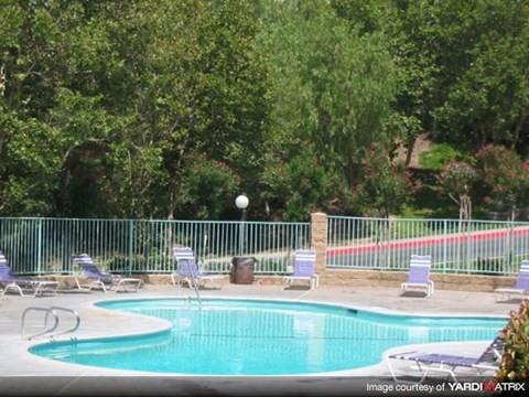 a swimming pool with chairs and a fence around it