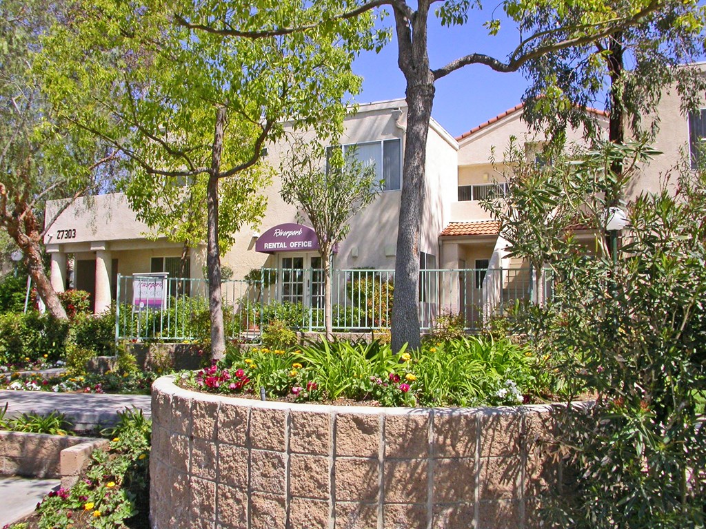 a large planter in front of a building with trees and plants