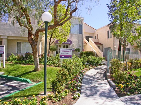 a sidewalk in front of an apartment building with a sign