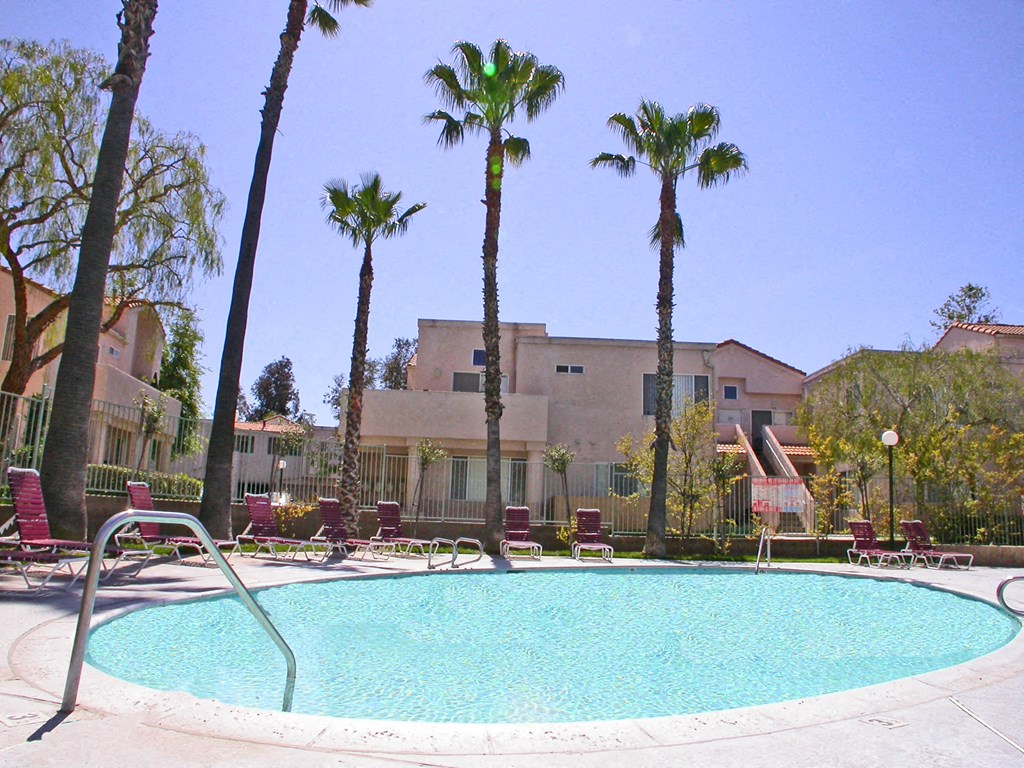 a pool with palm trees and a building in the background