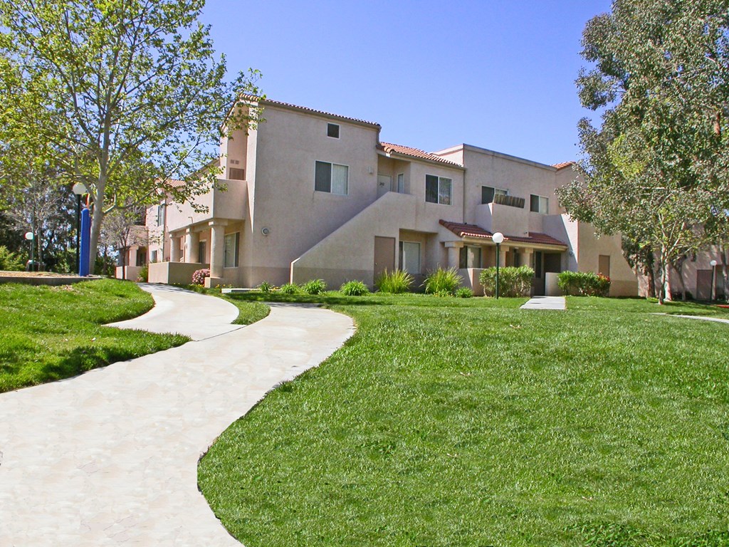 a sidewalk leading to a building with grass and trees