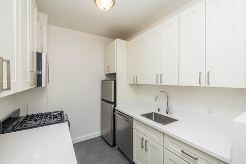 A kitchen with white cabinets and a black stove top.