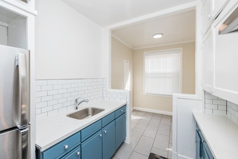 A kitchen with blue cabinets and a white counter.