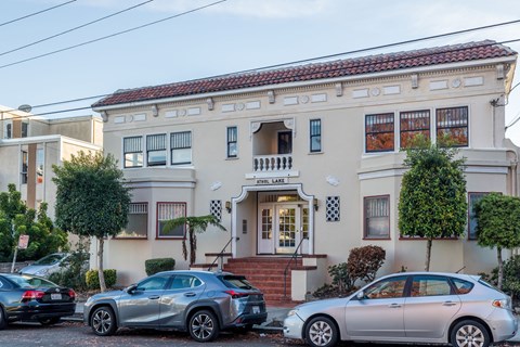 Two cars are parked in front of a building with a sign that reads "Crest Lake.".