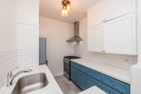 A kitchen with a stainless steel sink and a stove top oven.