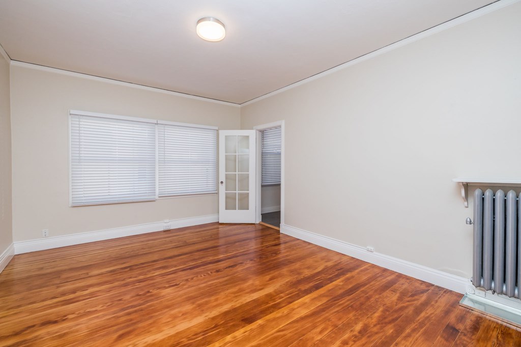 a living room with wood floors and a radiator and a window