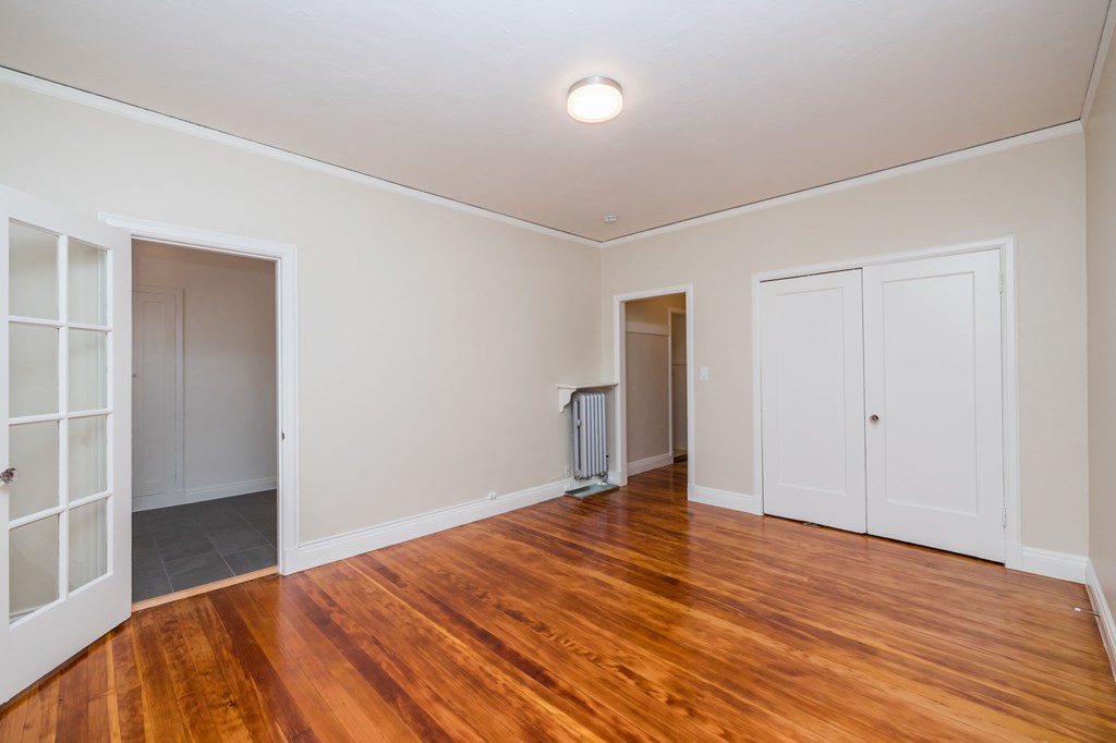 an empty living room with wood floors and white walls