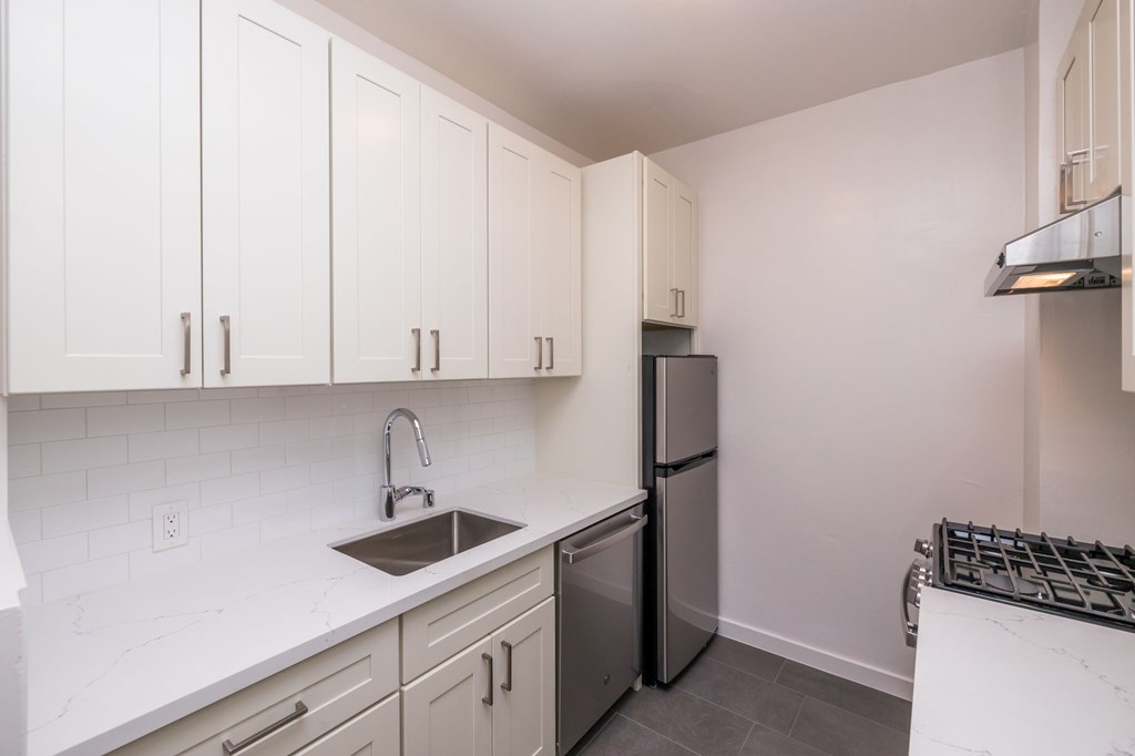 a kitchen with white cabinets and a sink and a refrigerator