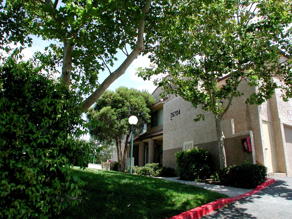 a sidewalk in front of a building with trees