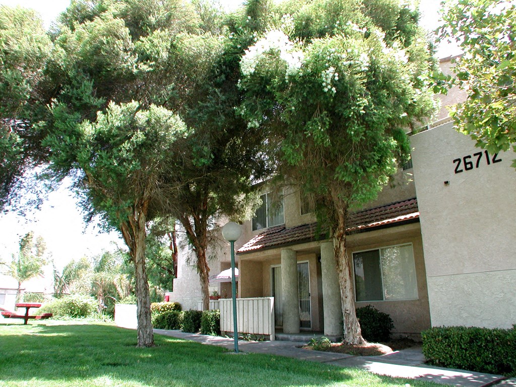 a building with a yard and trees in front of it