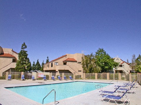 an outdoor pool with chairs and a building in the background