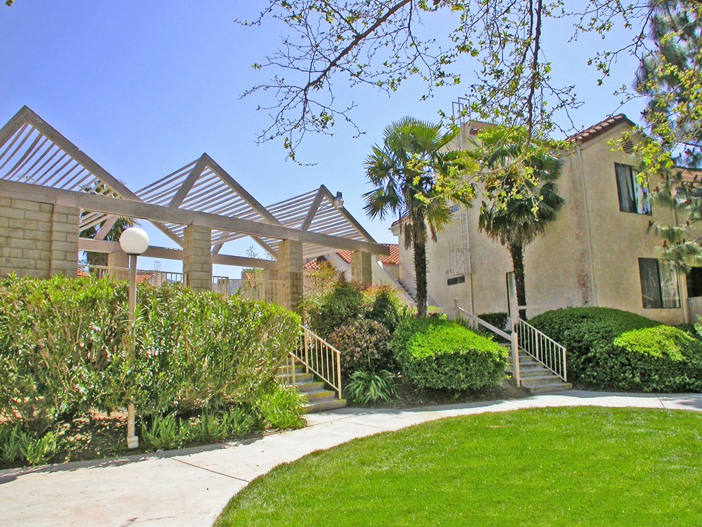 a sidewalk in front of a building with palm trees