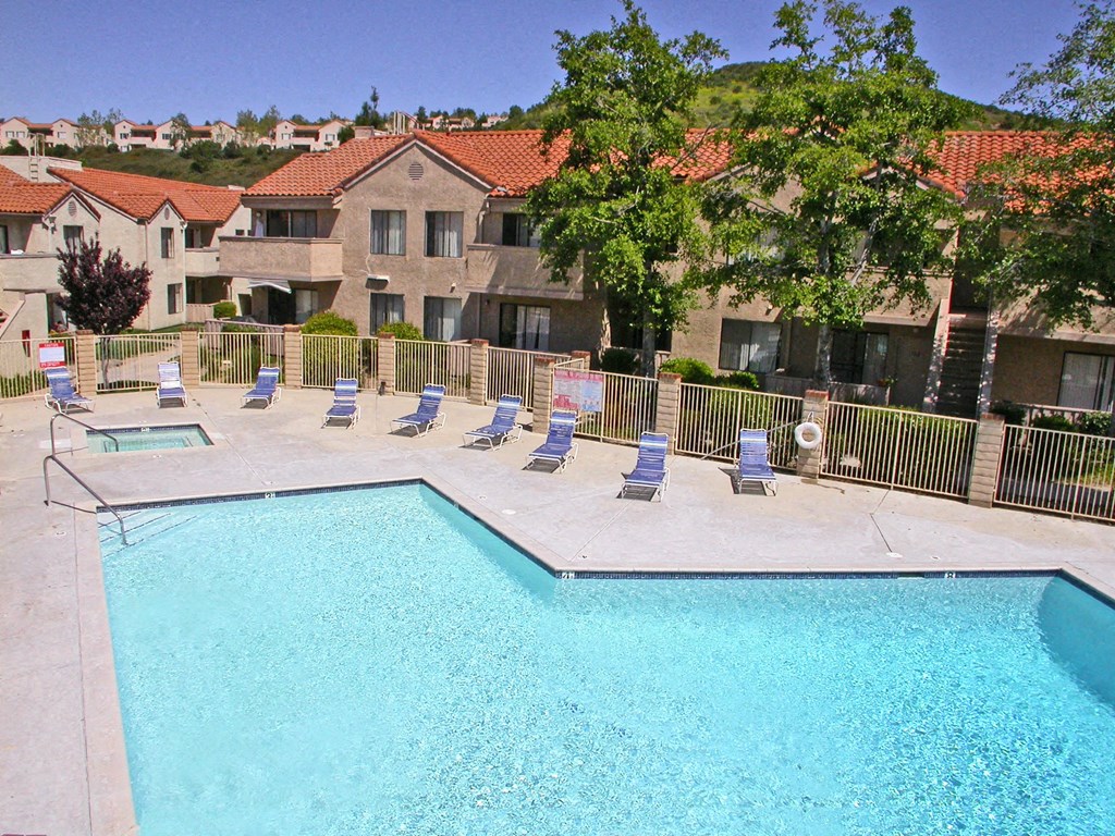 a swimming pool with chaise lounge chairs near a resort style pool