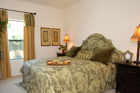 A bedroom with a large bed and a window with curtains.