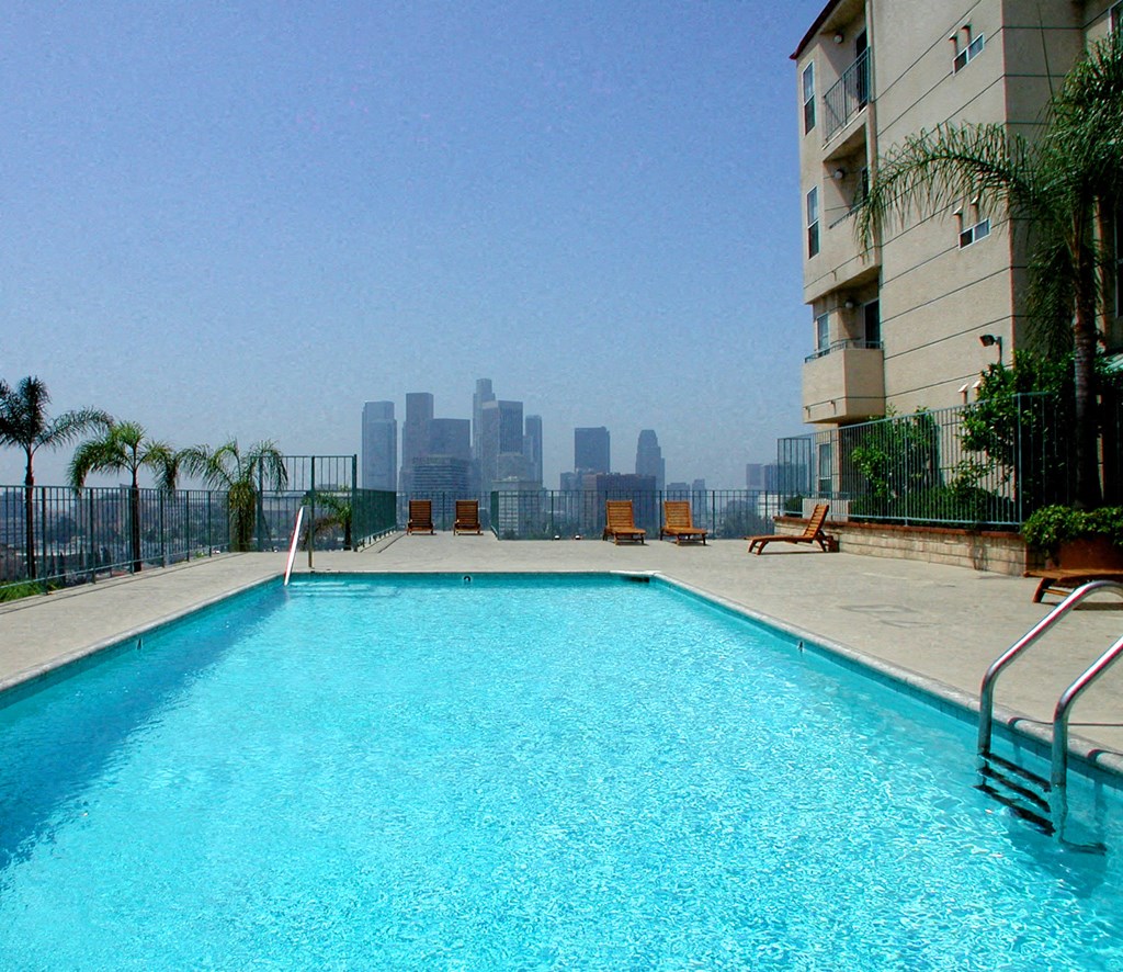 the pool on the roof of an apartment building with a view of the city