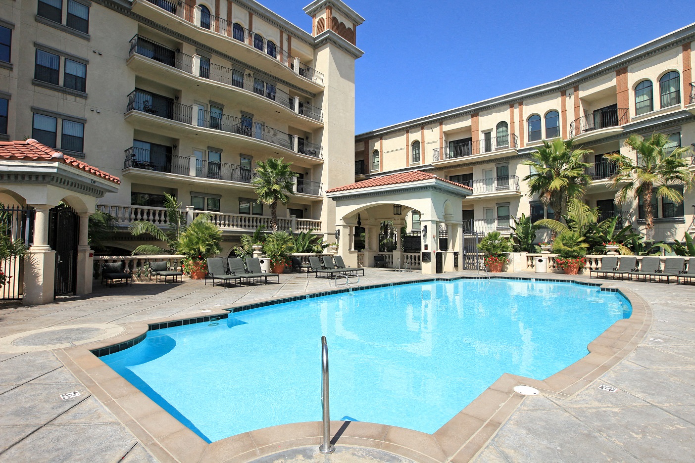 A large swimming pool in front of a building with a balcony.