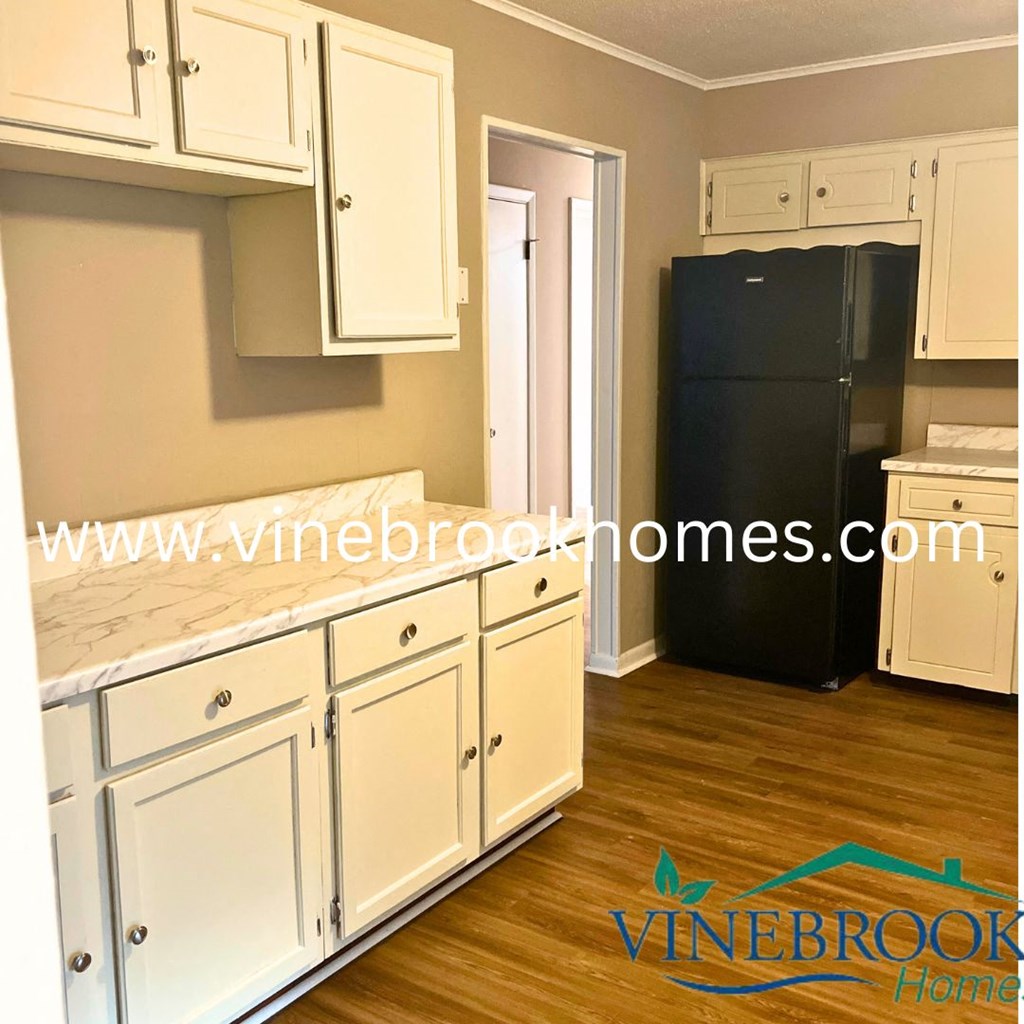a kitchen with white cabinets and a black refrigerator