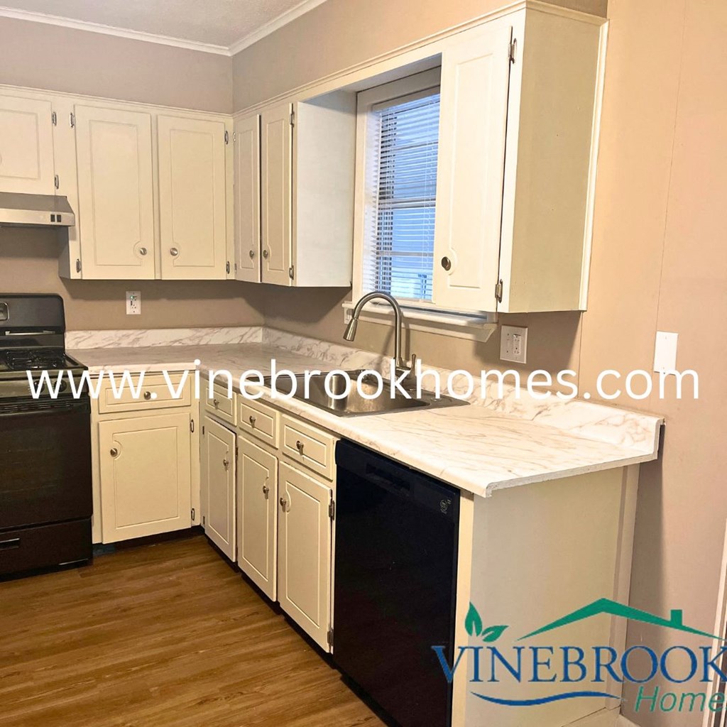 a kitchen with white cabinets and a black dishwasher