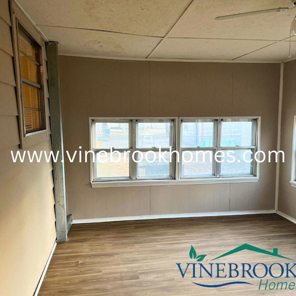 a living room with windows and a hard wood floor