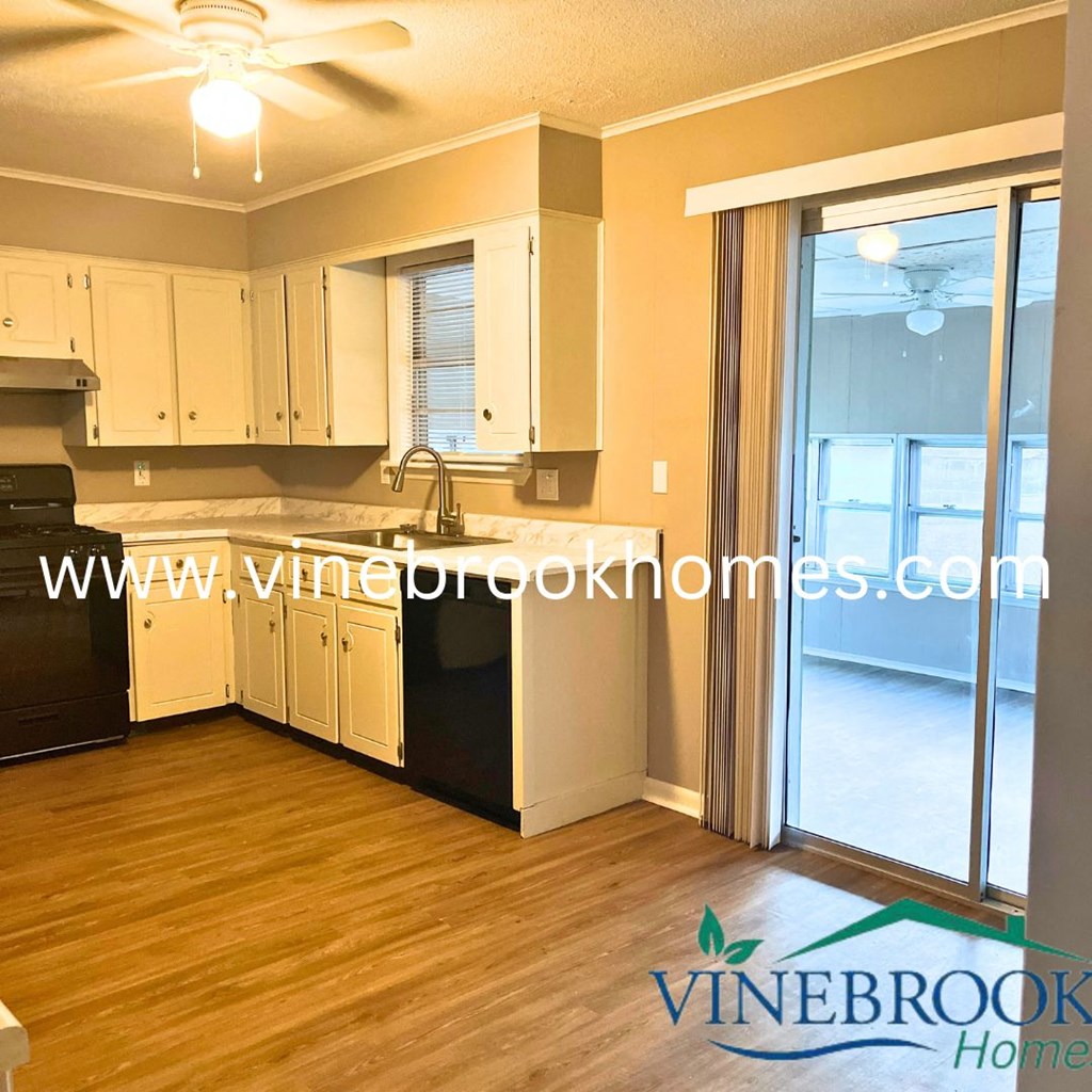 a kitchen with white cabinets and a sliding glass door