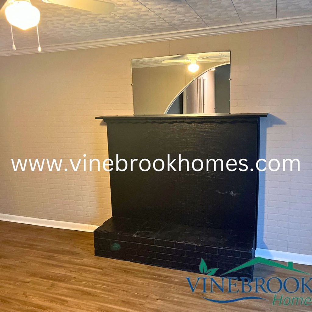 a fireplace in a living room with a mirror and a wood floor