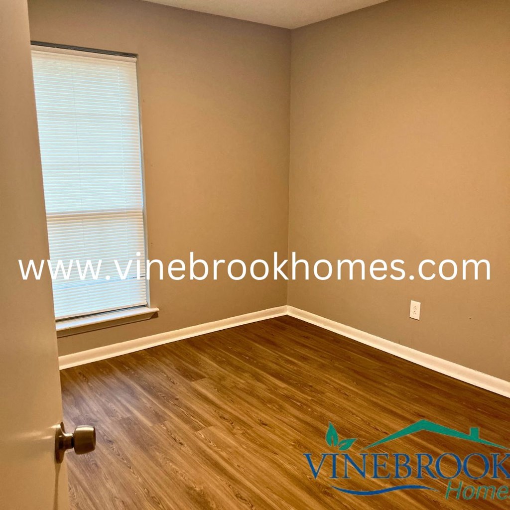 a bedroom with wood floors and a window