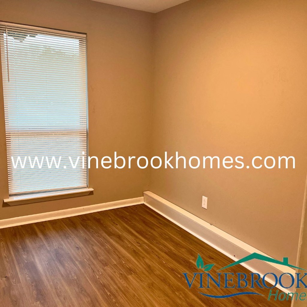a bedroom with a window and wooden floors