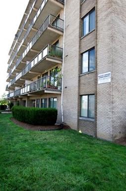 an apartment building with a green yard in front of it