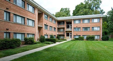 a large brick apartment building with a green yard