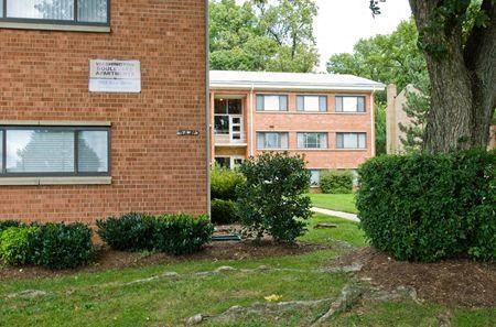 a brick building with a tree and bushes in front of it